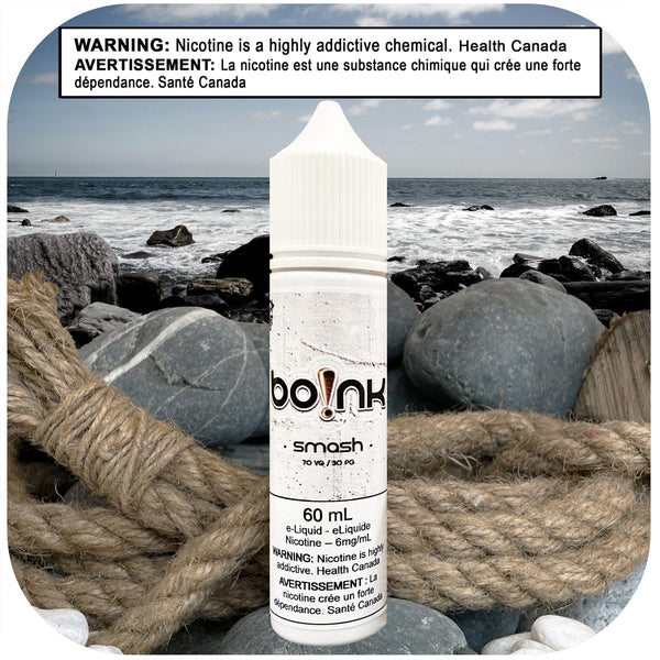 Boink Smash Strawberry Spearmint e-liquid bottle on a beach with ocean and rocks in the background
