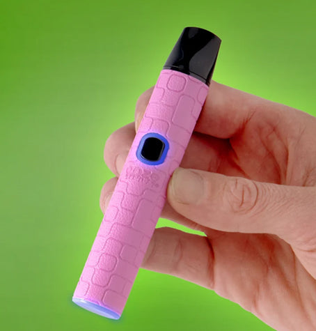 A hand holding a pink textured Ooze Pinch pink device with a black mouthpiece and blue accent details, set against a bright green gradient background.