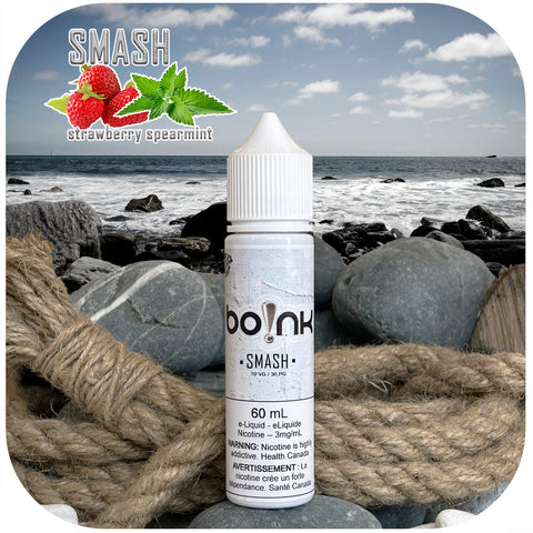 Boink Smash Strawberry Spearmint e-liquid bottle on a beach with ocean and rocks in the background