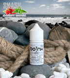 Boink Smash Strawberry Spearmint e-liquid bottle on a beach with ocean and rocks in the background