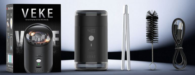 Yocan VEKE Electric Grinder shown with its retail box, the device itself, a metal cleaning tool, a bristle brush, and a USB charging cable on a dark studio background.